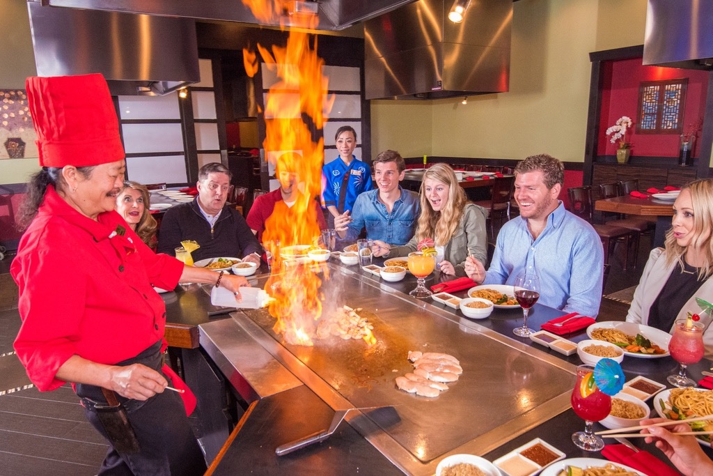 Guests sitting at Teppanyaki table with chef cooking.
