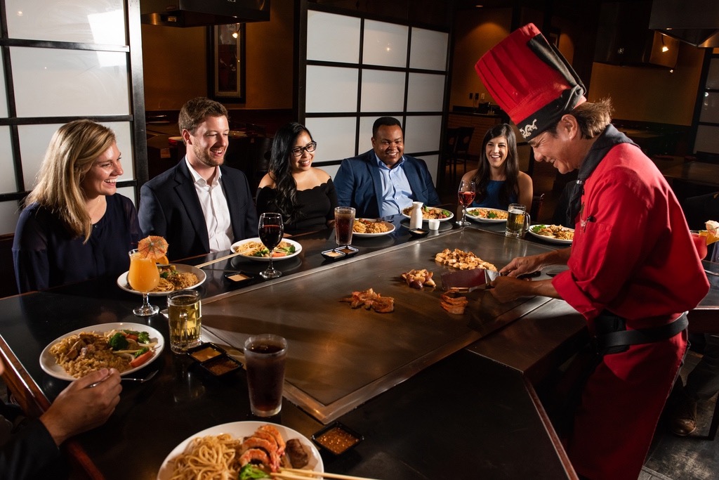Guests sitting at Teppanyaki table with chef cooking.
